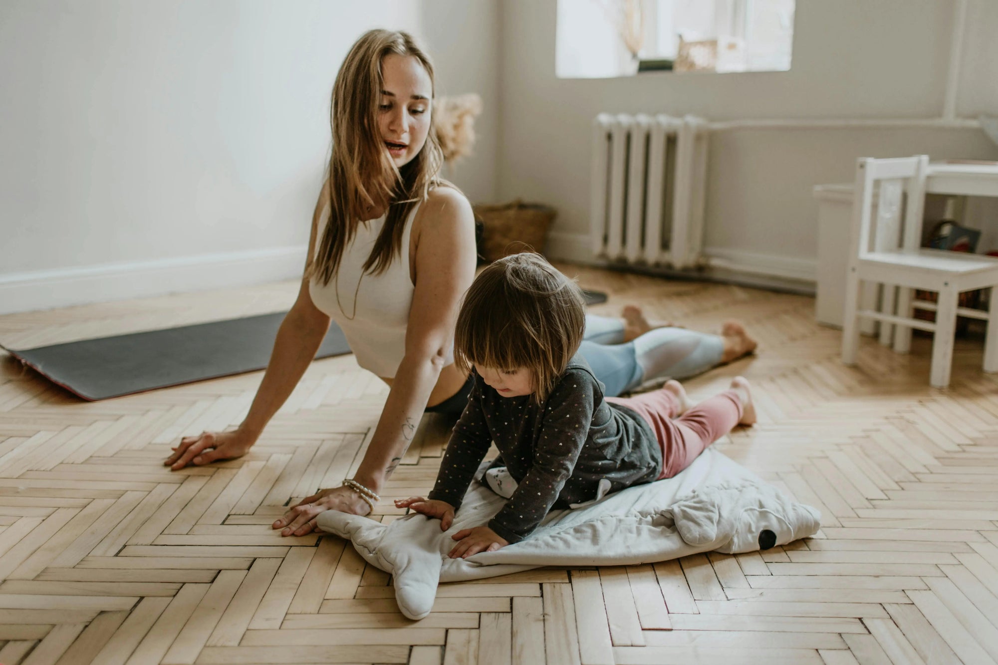 Maman et enfant qui font du yoga sur plancher en chevrons